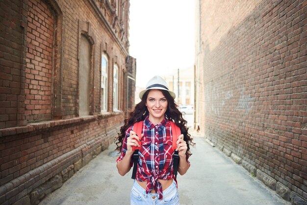 Retrato de una niña turista con un sombrero entre las casas de ladrillo rojo