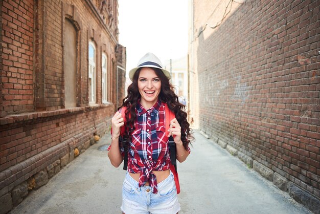 Retrato de una niña turista con un sombrero entre las casas de ladrillo rojo