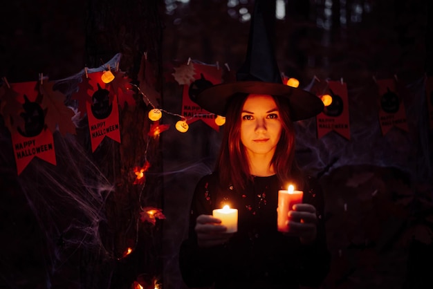 Retrato de una niña con velas brillantes en el bosque por la noche