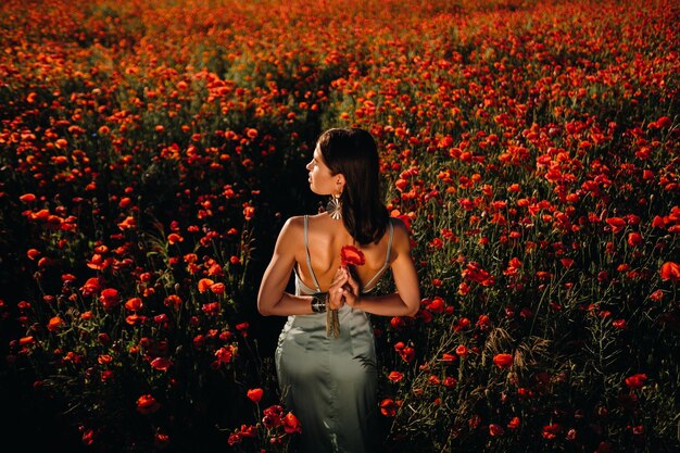 Retrato de una niña con un vestido en un campo de amapolas al atardecer