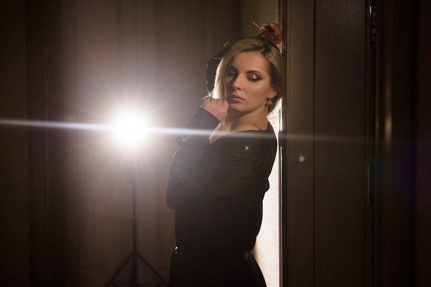 Foto retrato de una niña en un vestido negro posando en la luz de fondo