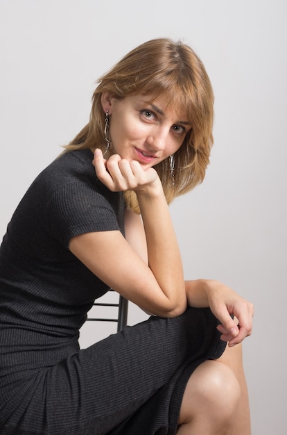 Retrato de una niña con un vestido negro sentada en una silla