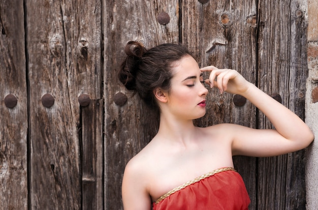 Retrato de una niña en vestido rojo en una puerta de madera