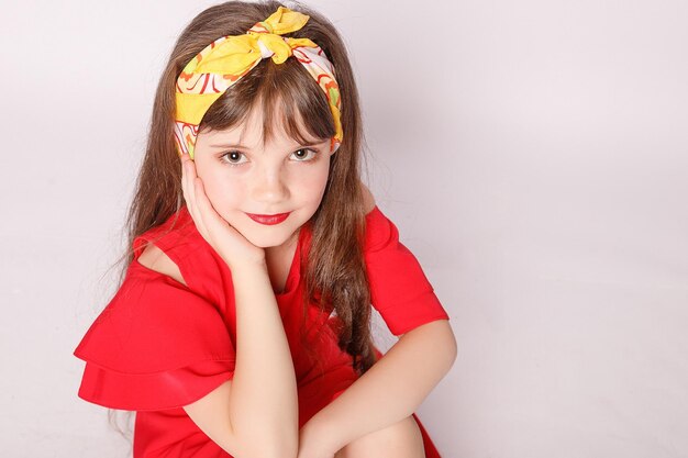 Retrato de una niña con un vestido rojo sobre un fondo blanco