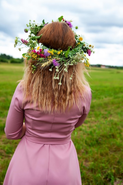 Retrato de niña en vestido rosa con corona de flores silvestres