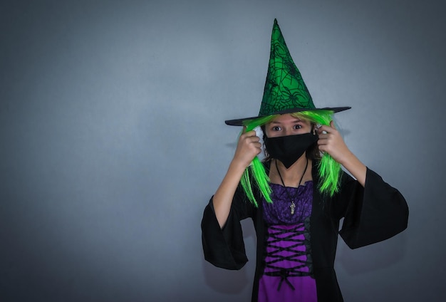 Retrato de una niña con un vestido de sombrero de Halloween y una máscara negra