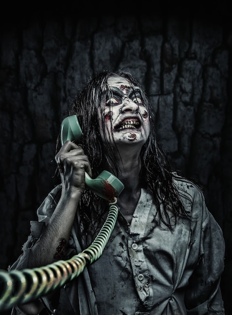 Foto retrato de la niña zombie de terror llamando por teléfono. aterrador