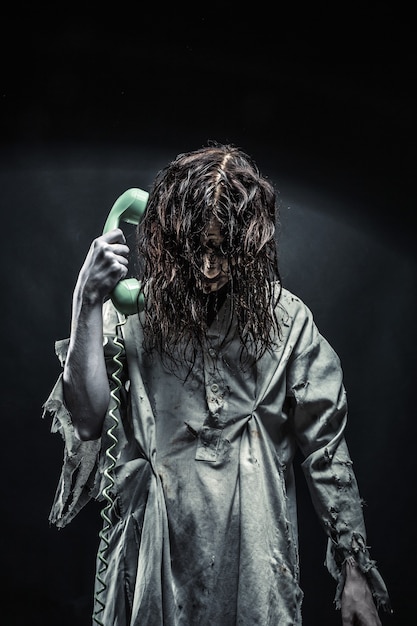 Foto retrato de la niña zombie de terror llamando por teléfono. aterrador