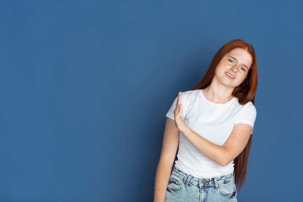 Retrato de niñas caucásicas en pared azul hermosa modelo pelirroja con lindas pecas