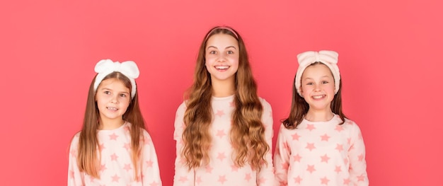 Retrato de niñas felices con caras sonrientes en fondo rosa homewear