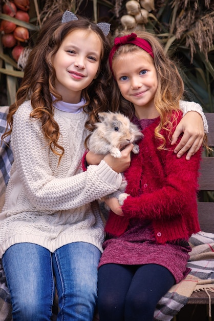 retrato de niñas novias en el otoño con un conejo en sus manos cerca de su casa fam