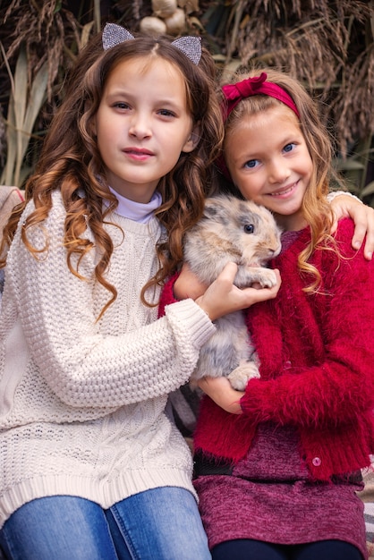 retrato de niñas novias en el otoño con un conejo en sus manos cerca de su casa fam