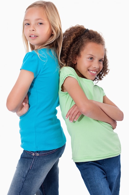 Retrato de niñas sonrientes de pie espalda con espalda