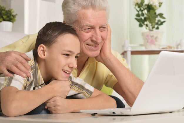 Retrato de niño y abuelo con un portátil en casa