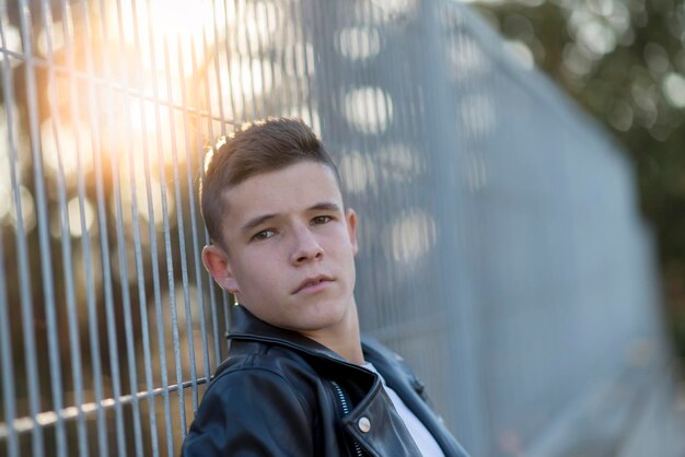Foto retrato de un niño adolescente apoyado en una valla
