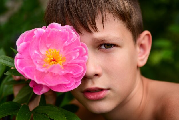 Retrato de un niño adolescente con una flor en el ojo