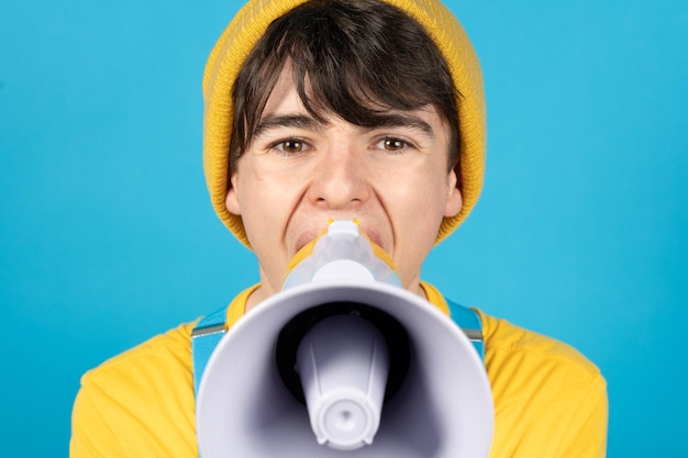 Foto retrato de niño adolescente gritando en altavoz o megáfono