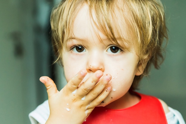 Foto retrato de niño adorable comiendo bizcocho de chocolate