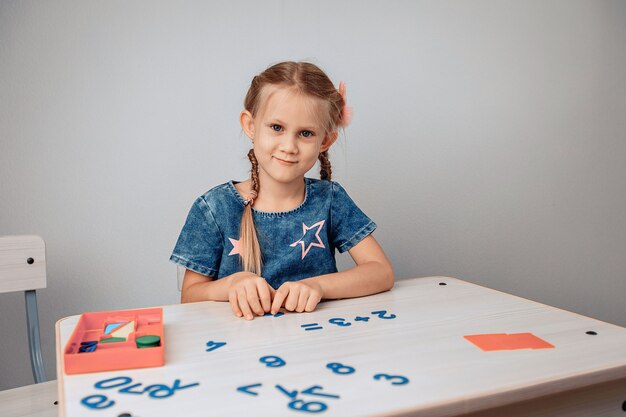 Retrato de un niño adorable muy sonriente sentado en una mesa blanca y estudiando números. Concepto de conocimientos. foto con ruido