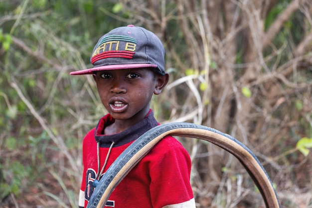 Retrato de un niño africano con un neumático de bicicleta. Madagascar.