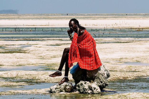 Retrato de un niño africano sentado en una piedra contra el telón de fondo del océano. Zanzíbar