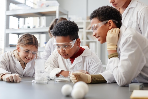 Retrato de un niño afroamericano disfrutando de experimentos científicos en clase de química y usando equipo de protección