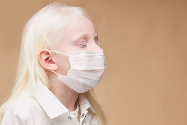 Retrato de niño albino místico enfermo en máscara médica aislada