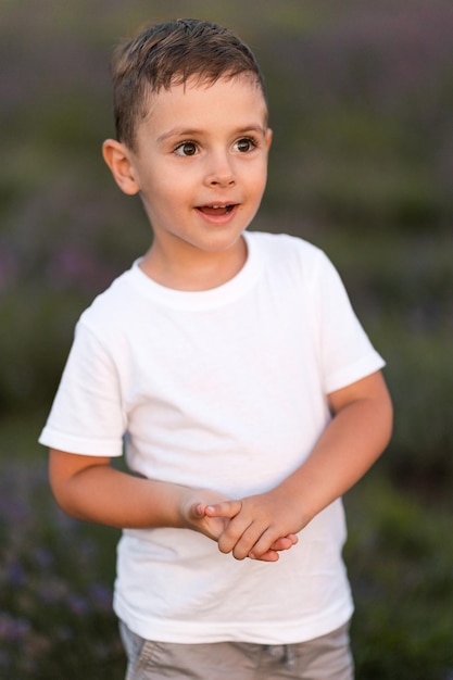 Retrato de niño alegre sonriendo y jugando en el campo de lavanda