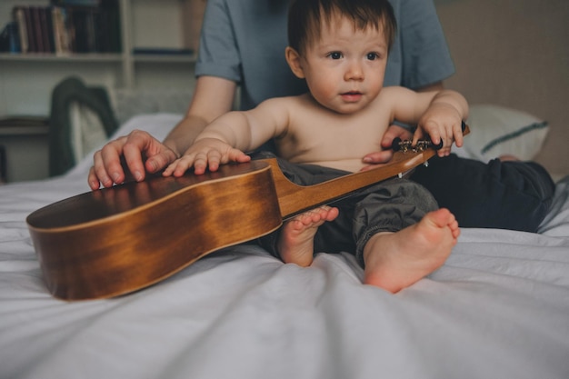 retrato de un niño de un año en una cama con un ukelele