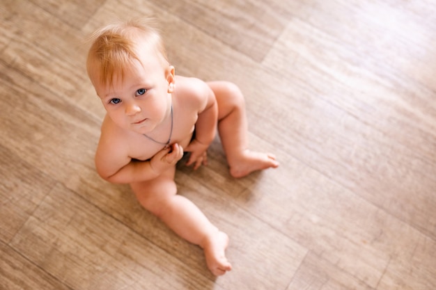 Retrato de un niño de un año sentado en el suelo. Niño bonito en casa