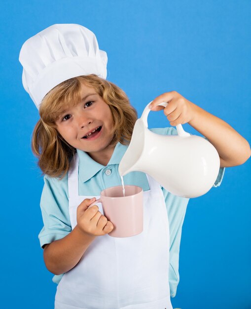 Retrato de un niño de años con gorra de cocinero y delantal haciendo ensalada de frutas y cocinando comida en la cocina