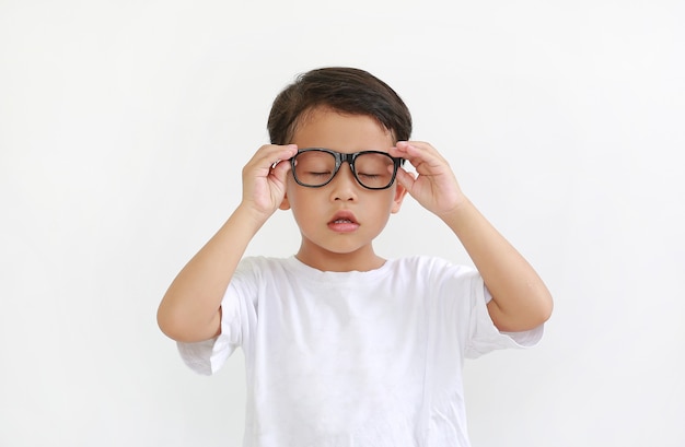 Retrato de niño asiático con los ojos cerrados con gafas aislado sobre fondo blanco.