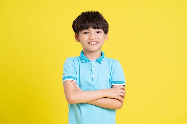 Retrato de un niño asiático posando sobre un fondo amarillo