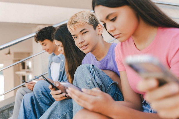 Foto retrato de un niño asiático sonriente con un teléfono inteligente jugando a un juego móvil mirando a la cámara tecnología