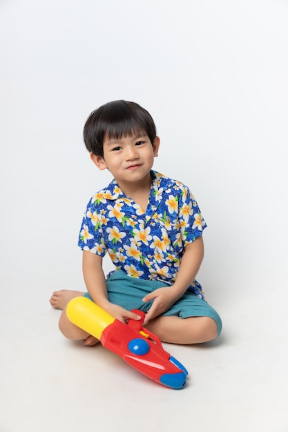 Retrato de niño asiático sonrió con pistola de agua