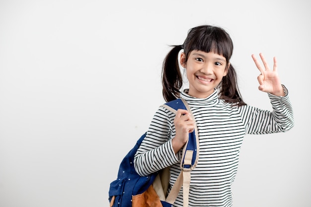 Retrato de niño asiático en uniforme escolar con mochila escolar sobre fondo blanco.