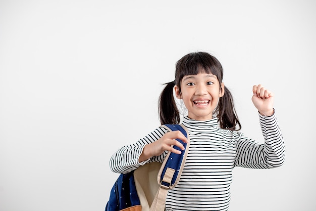 Retrato de niño asiático en uniforme escolar con mochila escolar sobre fondo blanco.