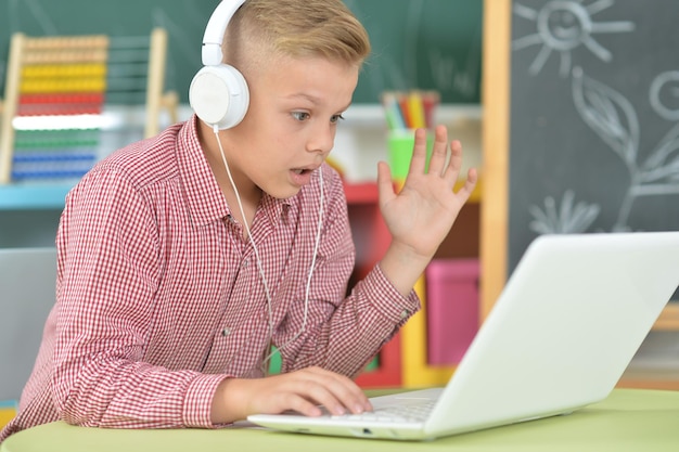 retrato, de, niño, con, auriculares, usar la computadora portátil