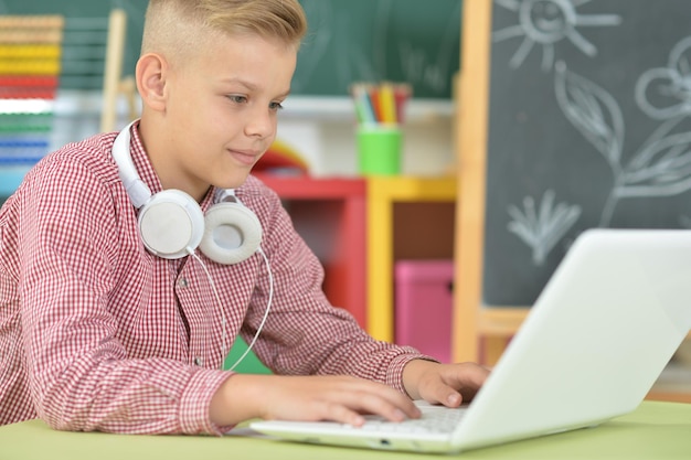 retrato, de, niño, con, auriculares, usar la computadora portátil