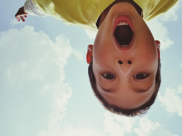 Retrato de un niño con la boca abierta contra el cielo