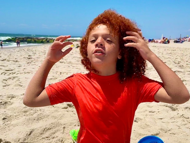 Foto retrato de un niño con los brazos levantados en la playa