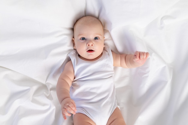 Retrato de un niño en una cama blanca por la mañana. Textiles y ropa de cama para niños. Un bebé recién nacido se ha despertado o se va a dormir.