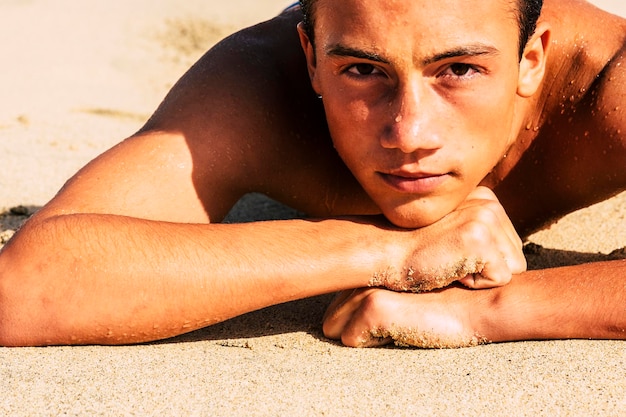 Foto retrato de un niño sin camisa tendido en la arena en la playa