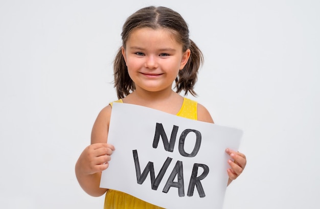 Retrato de un niño con un cartel sin guerra sobre un fondo gris