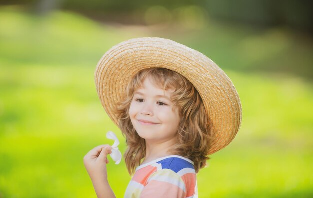 Retrato de niño caucásico de cerca Niños con sombrero de paja con flor de plumeria