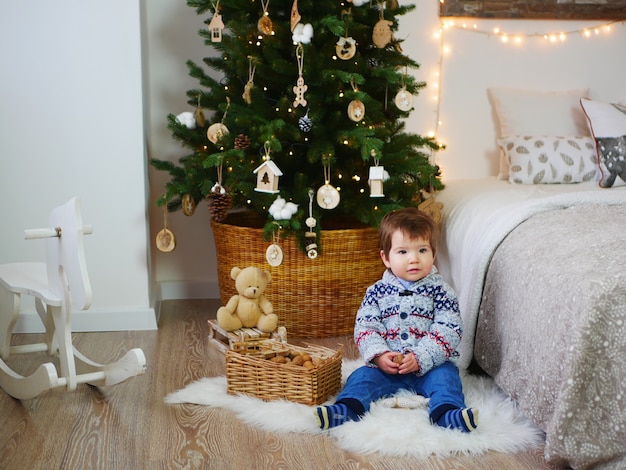 Retrato de un niño cerca de las decoraciones de año nuevo y un árbol