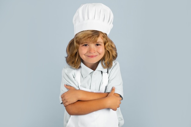 Retrato de niño chef aislado en azul Gracioso niño pequeño chef cocinero vistiendo uniforme gorro de cocinero y delantal comida cocinada en la cocina