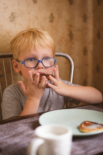 Retrato de niño chico rubio de 4 años comiendo panqueques