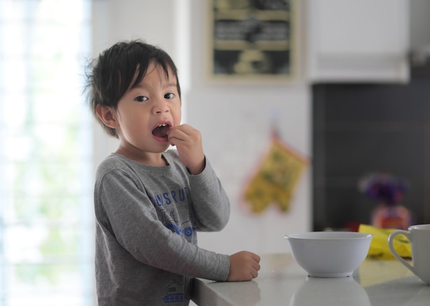 Retrato de un niño comiendo comida en la cocina