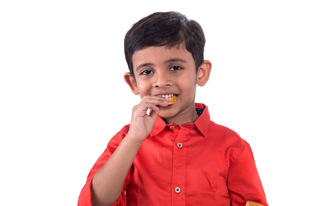 Retrato de niño comiendo una galleta en la pared blanca